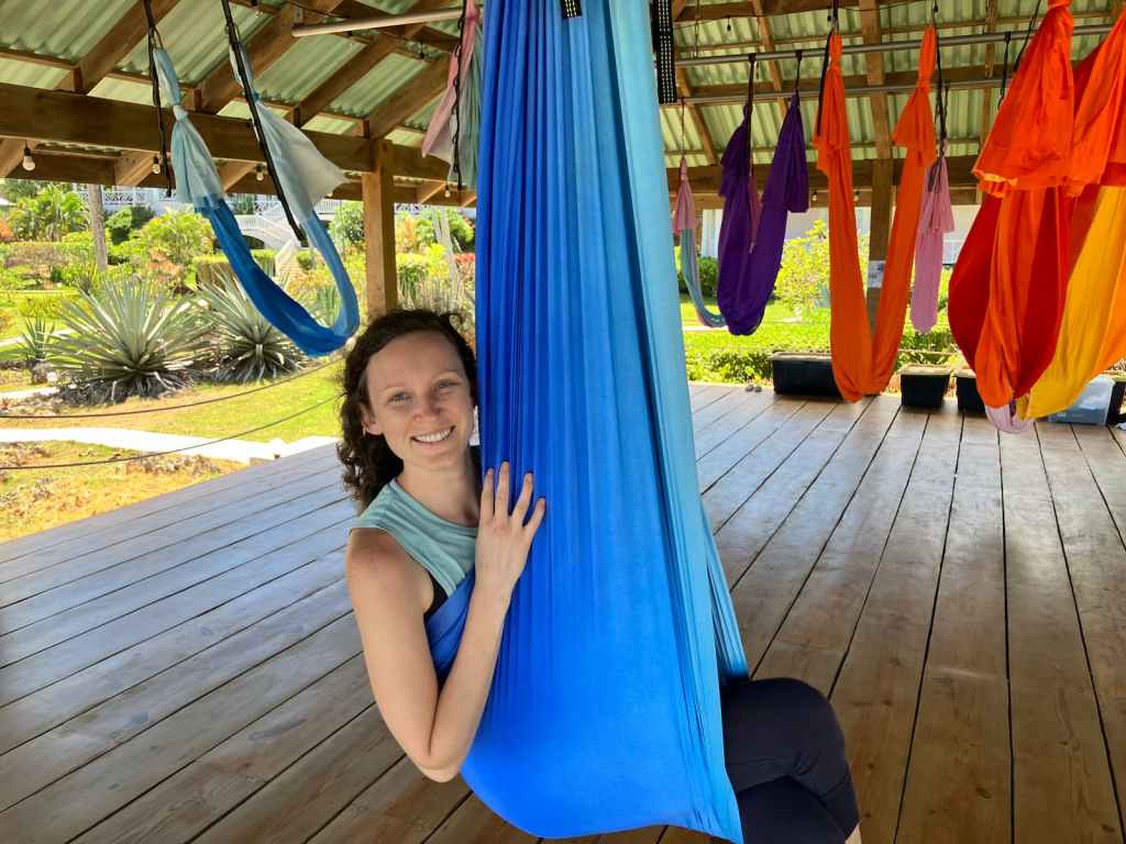 Kelsey sitting in blue aerial yoga hammock
